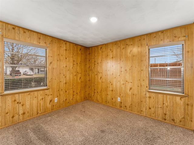 carpeted spare room featuring wood walls