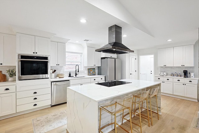 kitchen featuring a kitchen island, appliances with stainless steel finishes, island range hood, sink, and light stone counters