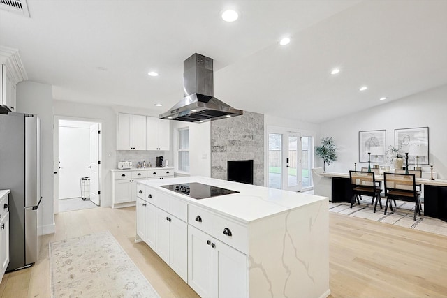 kitchen featuring stainless steel refrigerator, white cabinetry, black electric stovetop, island range hood, and a kitchen island