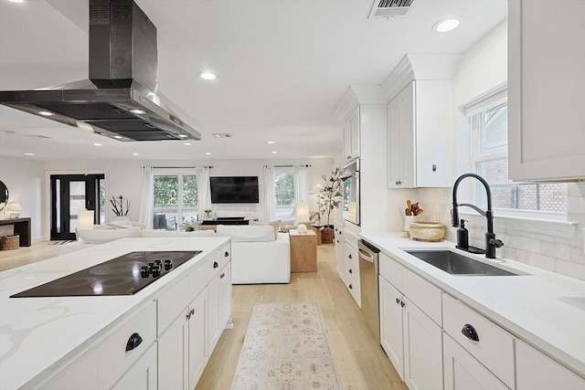 kitchen featuring white cabinetry, sink, island range hood, and appliances with stainless steel finishes