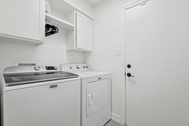 clothes washing area with cabinets and washing machine and dryer