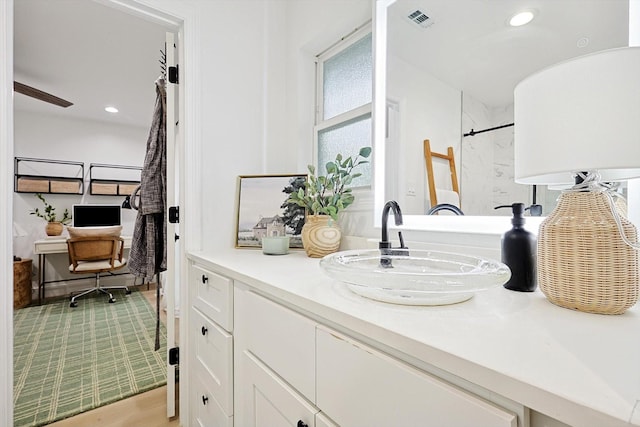 bathroom featuring hardwood / wood-style flooring, vanity, and walk in shower