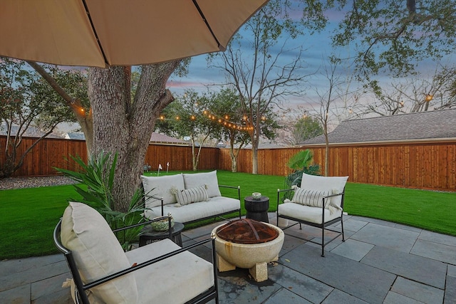 patio terrace at dusk featuring a yard and an outdoor living space with a fire pit