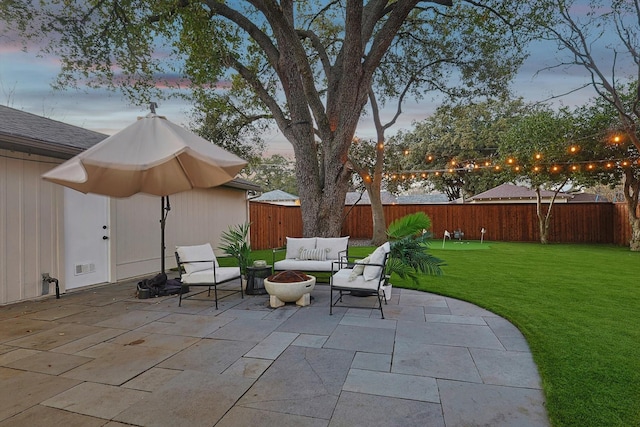 patio terrace at dusk with a yard and an outdoor living space with a fire pit