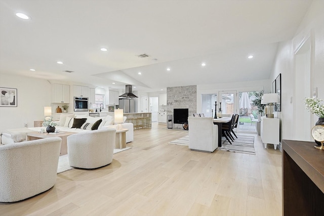 living room with lofted ceiling, a fireplace, and light wood-type flooring