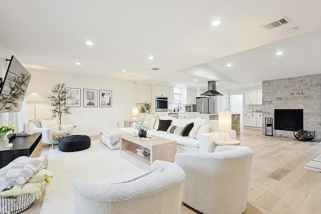 living room with sink, light hardwood / wood-style floors, and a tile fireplace