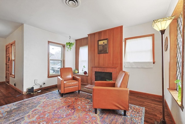 living area featuring a brick fireplace and dark hardwood / wood-style floors