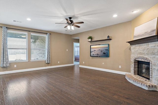 unfurnished living room with dark wood-style flooring, a fireplace, visible vents, a ceiling fan, and baseboards