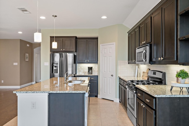 kitchen featuring dark brown cabinetry, a center island with sink, visible vents, appliances with stainless steel finishes, and a sink