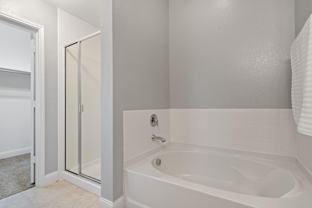 bathroom featuring a spacious closet, a shower stall, a bath, baseboards, and tile patterned floors