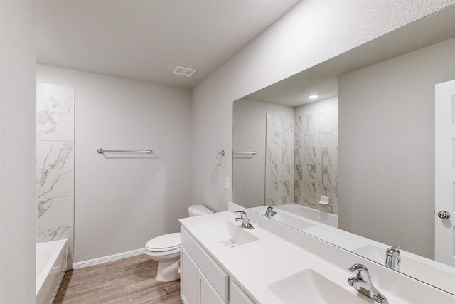 full bathroom with wood-type flooring, tiled shower / bath, vanity, and toilet