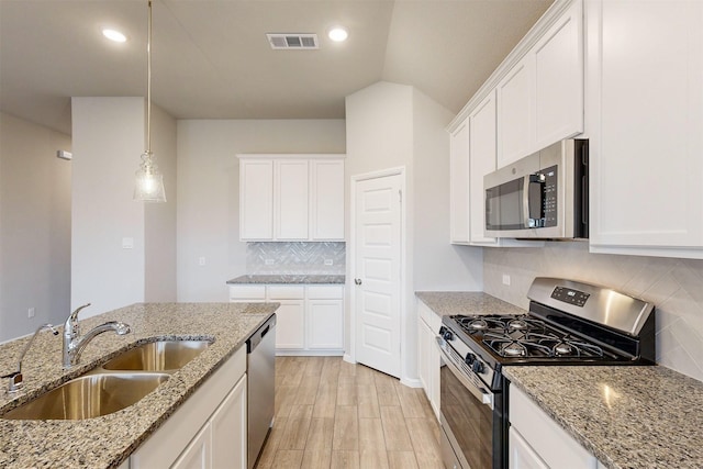 kitchen featuring sink, white cabinets, hanging light fixtures, stainless steel appliances, and light stone countertops