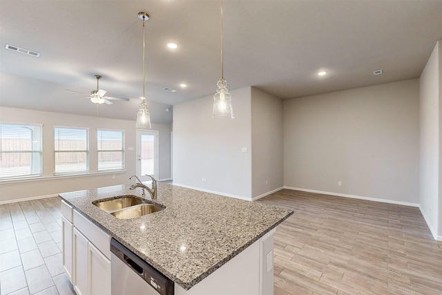 kitchen featuring an island with sink, sink, stainless steel dishwasher, and white cabinets