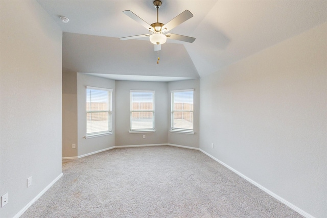 carpeted spare room featuring vaulted ceiling and ceiling fan