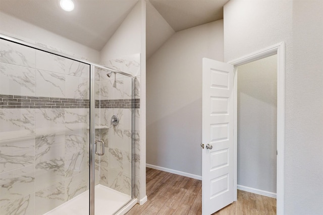 bathroom with lofted ceiling, an enclosed shower, and hardwood / wood-style floors