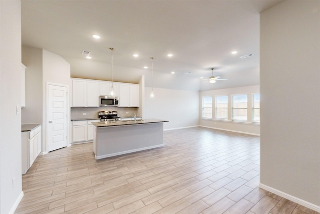 kitchen with white cabinetry, a center island with sink, appliances with stainless steel finishes, pendant lighting, and ceiling fan