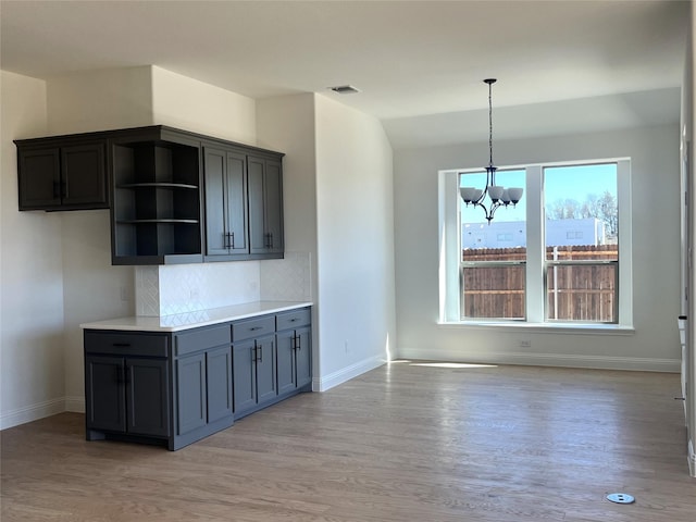 kitchen with open shelves, tasteful backsplash, visible vents, light wood-type flooring, and baseboards