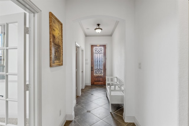 entryway featuring dark tile patterned flooring and crown molding