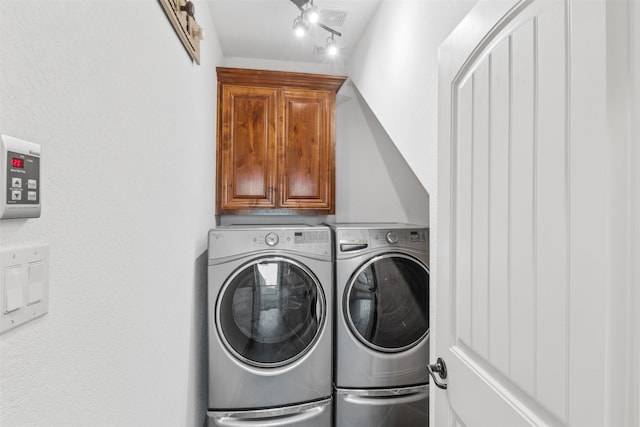 laundry area with rail lighting, cabinets, and washing machine and clothes dryer