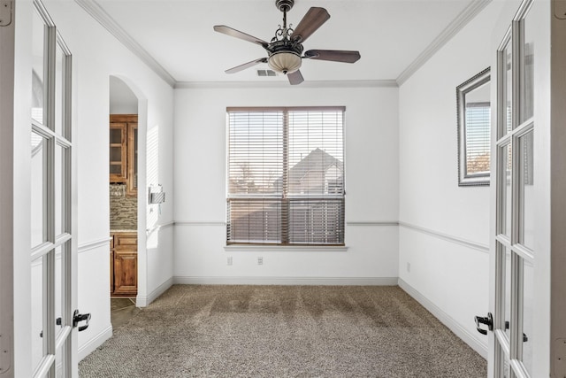 carpeted empty room with crown molding, french doors, and ceiling fan