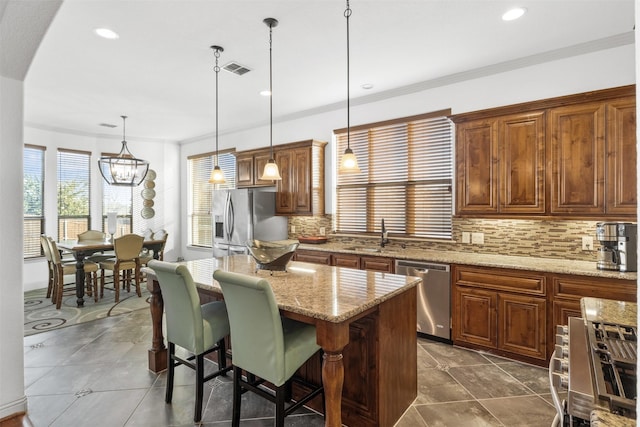 kitchen featuring a breakfast bar, decorative light fixtures, appliances with stainless steel finishes, a kitchen island, and light stone countertops