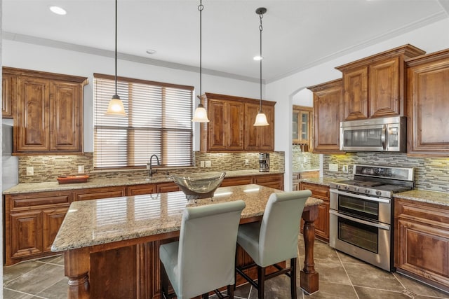 kitchen featuring sink, a breakfast bar area, a center island, light stone counters, and stainless steel appliances