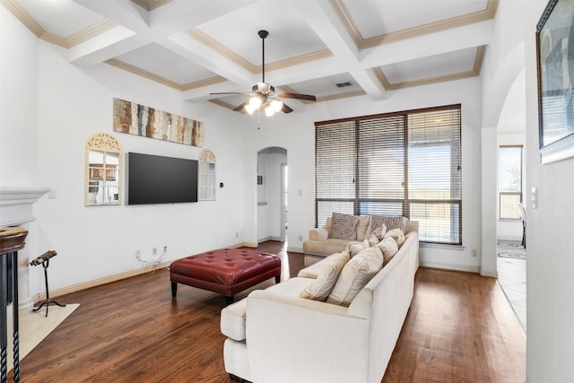 living room featuring dark wood-type flooring, coffered ceiling, crown molding, beamed ceiling, and ceiling fan