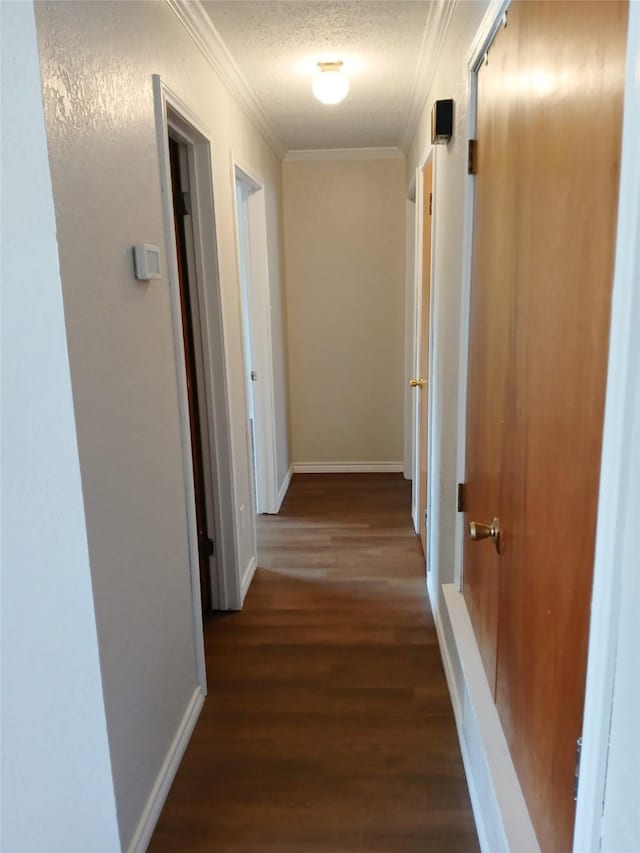 hall featuring ornamental molding, dark wood-type flooring, and a textured ceiling