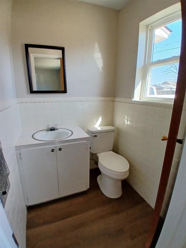 bathroom with hardwood / wood-style flooring, vanity, toilet, and tile walls