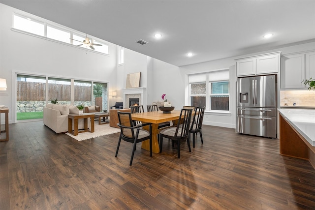 dining area with ceiling fan, dark hardwood / wood-style flooring, and a high ceiling