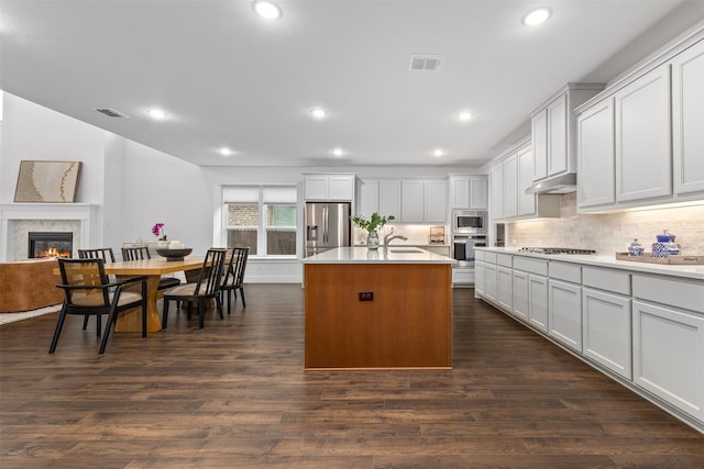 kitchen with sink, a center island with sink, appliances with stainless steel finishes, dark hardwood / wood-style flooring, and white cabinets