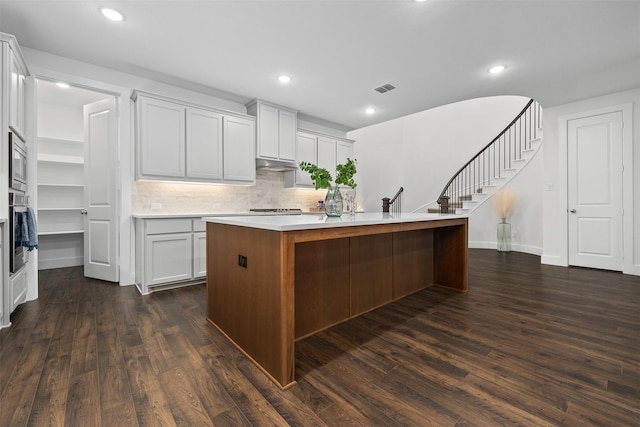 kitchen with a kitchen island with sink, white cabinetry, dark hardwood / wood-style floors, and appliances with stainless steel finishes