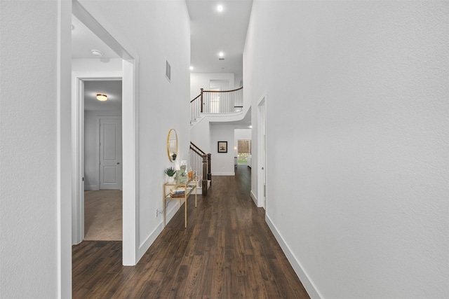 corridor featuring a towering ceiling and dark hardwood / wood-style floors