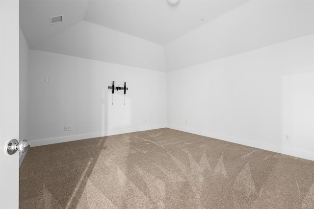 spare room featuring carpet flooring and vaulted ceiling