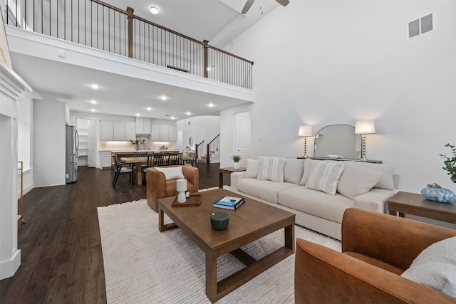 living room with dark hardwood / wood-style flooring, ceiling fan, and a high ceiling