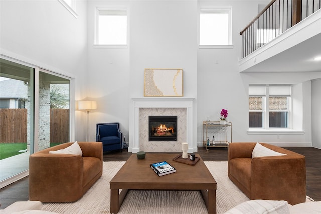 living room with hardwood / wood-style flooring, plenty of natural light, a towering ceiling, and a fireplace