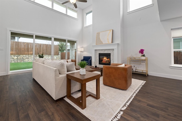 living room featuring a premium fireplace, dark hardwood / wood-style floors, and ceiling fan