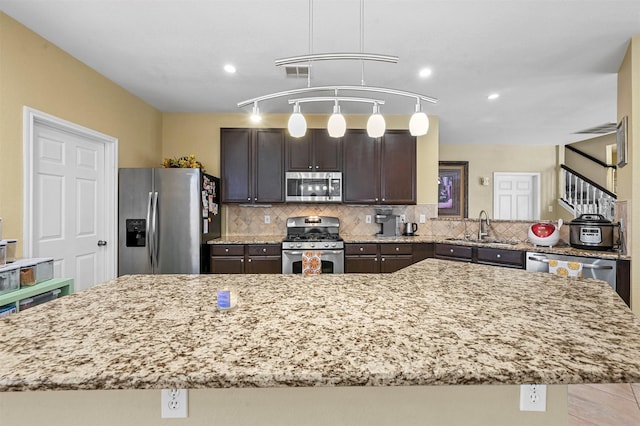 kitchen with appliances with stainless steel finishes, sink, a kitchen island, and backsplash