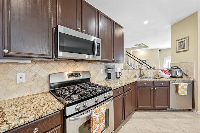 kitchen featuring tasteful backsplash, sink, light tile patterned floors, light stone counters, and stainless steel appliances