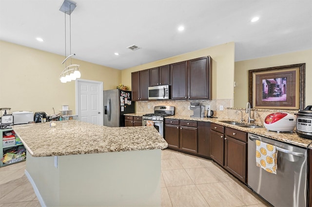 kitchen featuring sink, tasteful backsplash, hanging light fixtures, appliances with stainless steel finishes, and a kitchen island