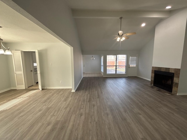 unfurnished living room with a tiled fireplace, ceiling fan with notable chandelier, dark hardwood / wood-style flooring, and beamed ceiling