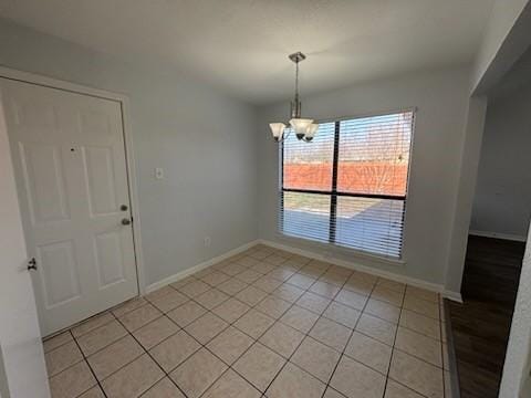 unfurnished dining area with an inviting chandelier and light tile patterned flooring