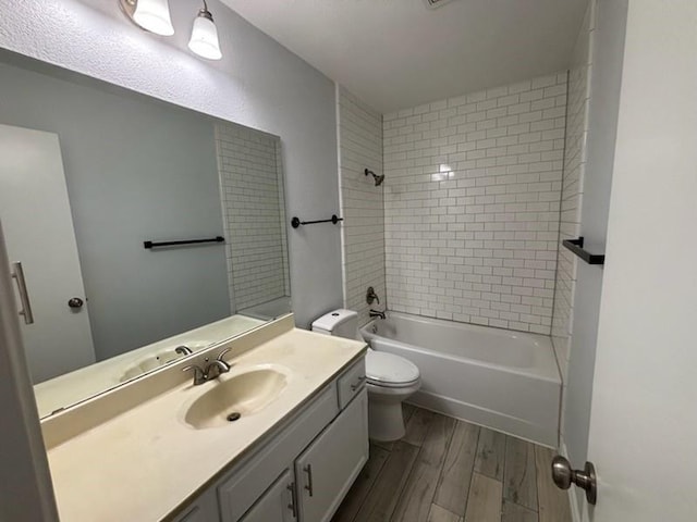 full bathroom featuring tiled shower / bath, hardwood / wood-style floors, vanity, and toilet