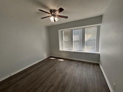 spare room with dark wood-type flooring and ceiling fan