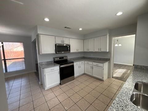 kitchen featuring light stone counters, stainless steel appliances, and white cabinets