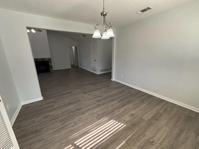 unfurnished dining area featuring an inviting chandelier, dark wood-type flooring, and a textured ceiling