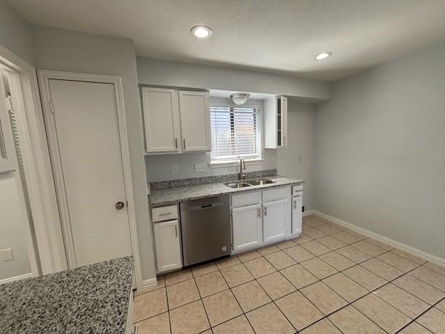 kitchen featuring light tile patterned flooring, sink, stainless steel dishwasher, light stone countertops, and white cabinets