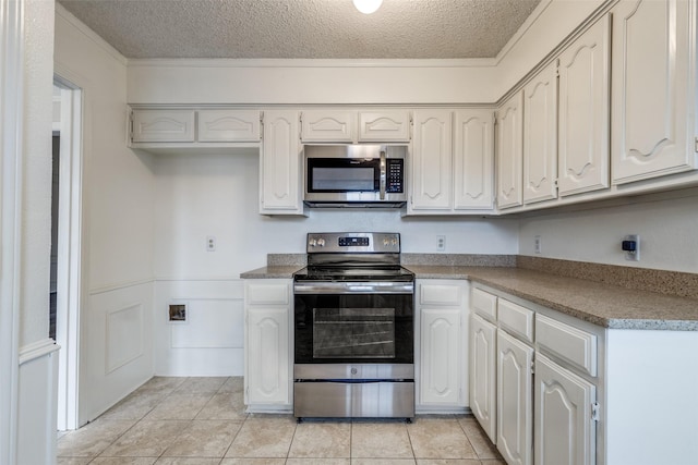 kitchen featuring stainless steel appliances, white cabinetry, light tile patterned flooring, and a textured ceiling