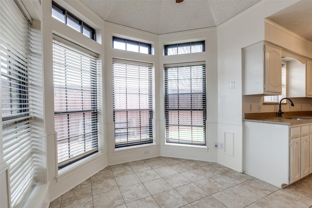 unfurnished dining area with sink, light tile patterned floors, a wealth of natural light, and a textured ceiling