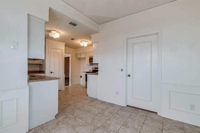 kitchen featuring light tile patterned flooring, appliances with stainless steel finishes, white cabinets, and a textured ceiling